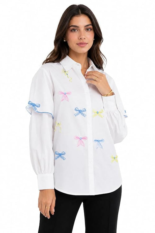 Woman wearing a white blouse with colorful bow patterns on a white background