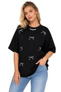 Woman wearing a black t-shirt with white bow designs and light blue jeans on a white background