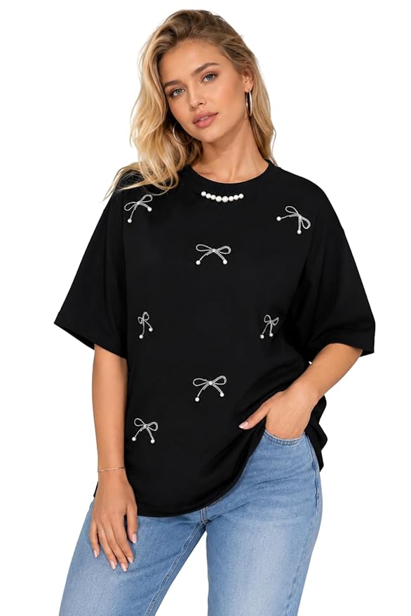 Woman wearing a black t-shirt with white bow designs and light blue jeans on a white background