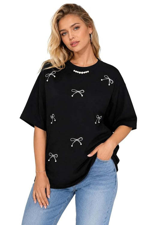 Woman wearing a black t-shirt with white bow designs and light blue jeans on a white background
